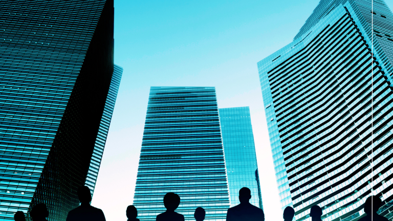 Low-angle view of glass commercial towers against a blue sky, representing SME and business growth